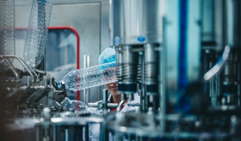 Experienced female supervisors regularly inspect an automated bottling process at a water pipeline manufacturing plant for accuracy of sequence, safety, and reliability. Day-to-day quality control.